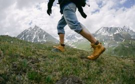 Randonneur gravissant un sentier de montagne verdoyant en chaussures de marche