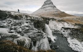 Randonneur marchant devant la montagne Kirkjufell givrée en Islande