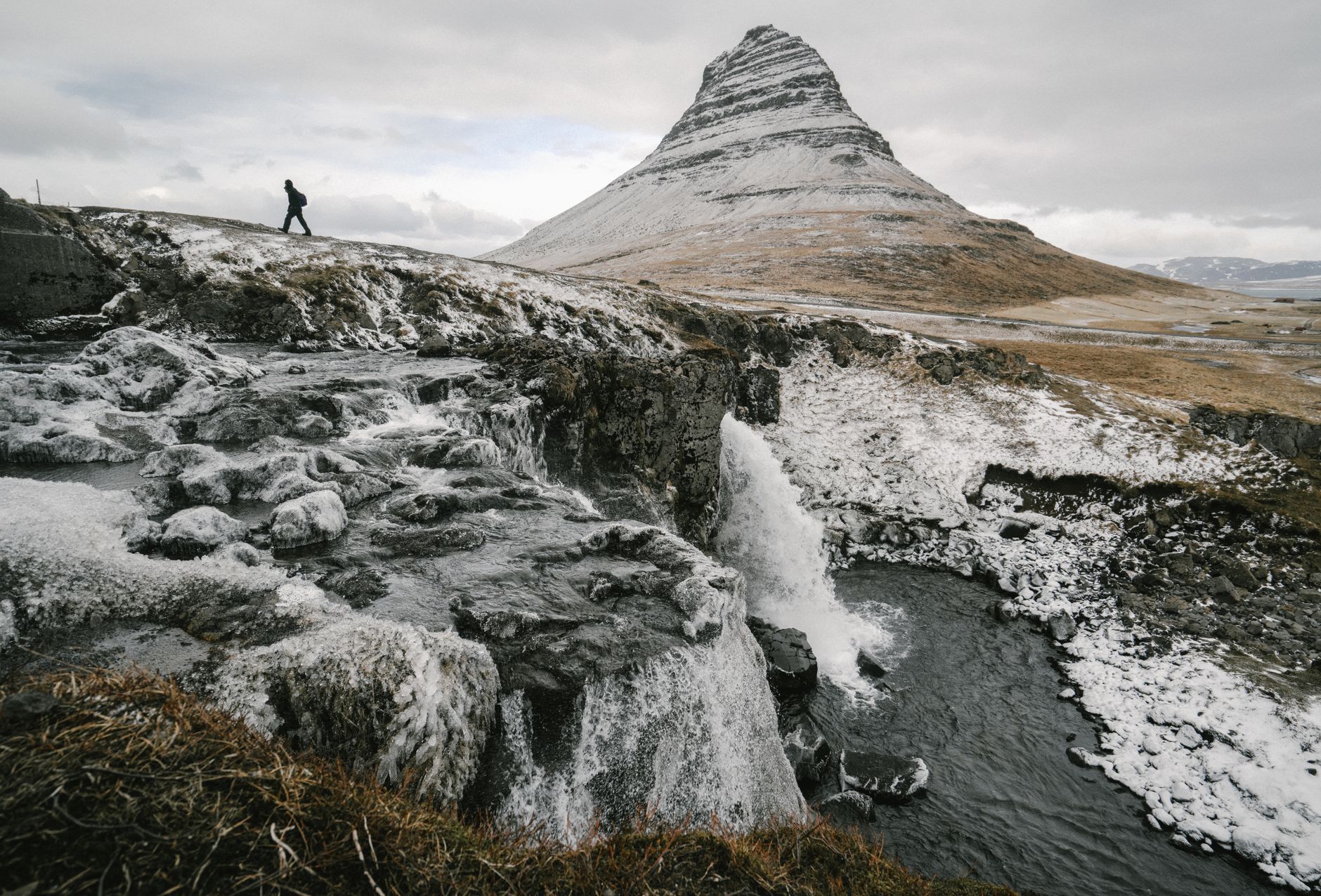Randonneur marchant devant la montagne Kirkjufell givrée en Islande
