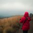 Randonneuse en veste imperméable rouge sur un sentier de lande sous le crachin